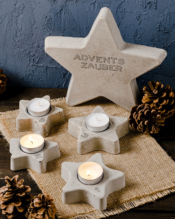 Adventskranz Beton-Sterne dekoriert mit Kerzen und Tannenzapfen