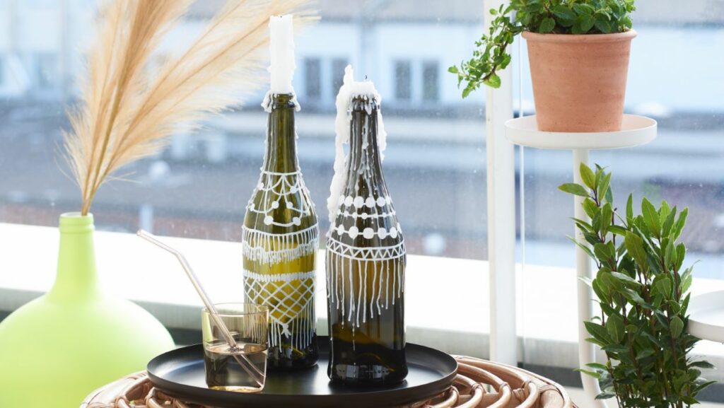Stimmungsvolle Weinflaschenleuchter mit Kerzen auf Tablett