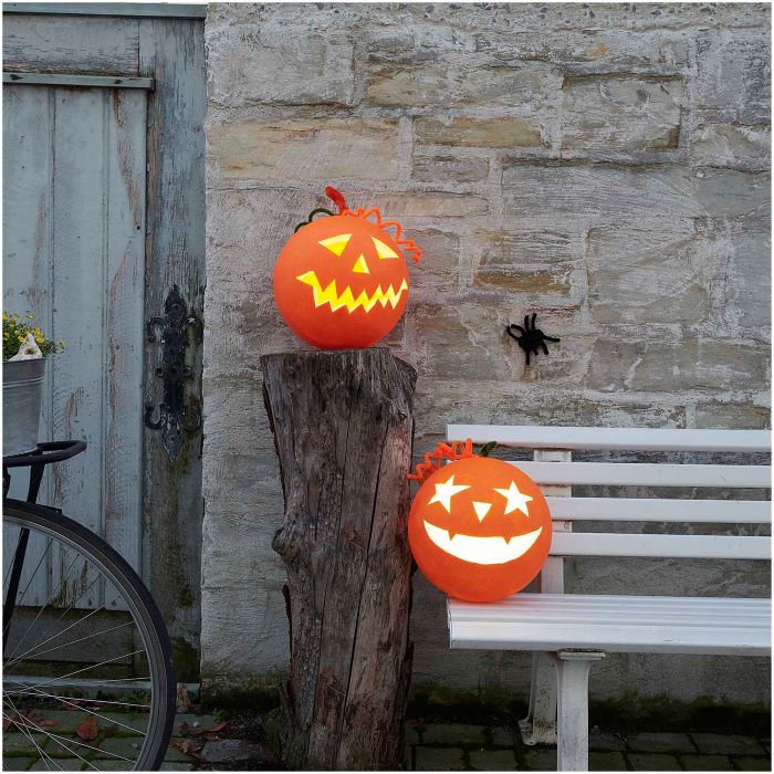 leuchtende Halloweenkürbisse auf einer Bank und auf einem Baumstumpf