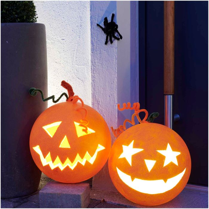Zwei leuchtende Halloweenkürbisse mit Spinne an der Hauswand
